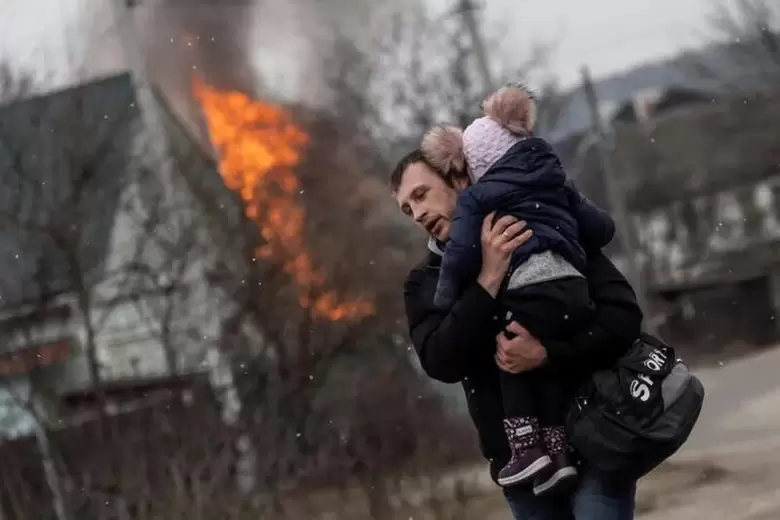 Un padre con su hijo escapa de su casa bombardeada por rusos