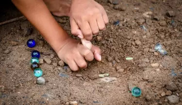 child-playing-glass-balls-on-the-soil-free-photo