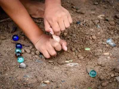 child-playing-glass-balls-on-the-soil-free-photo